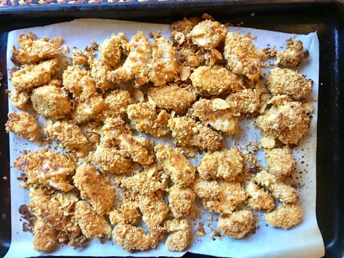 Baking Cornflake Chicken Nuggets in a sheet pan lined with parchment paper