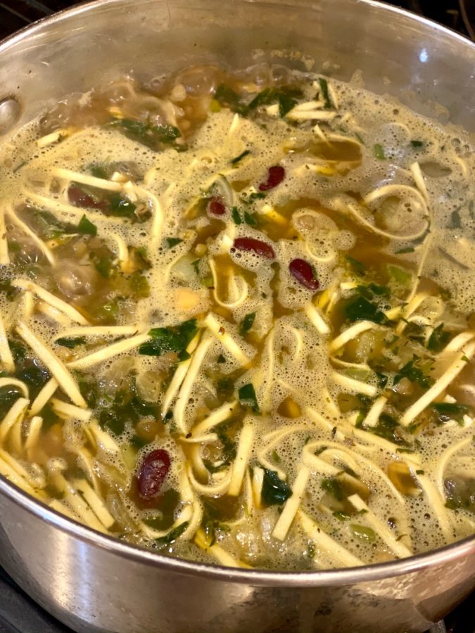 Cooking and simmering Ash Reshteh Persian Noodle Soup in a Big Pot