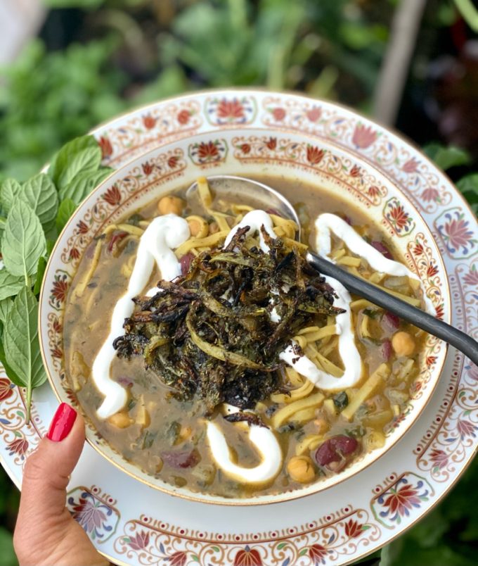 Ash Reshteh Persian Noodle and Bean Soup in a Bowl served with Onion garlic mint topping and kashk yogurt or sour cream