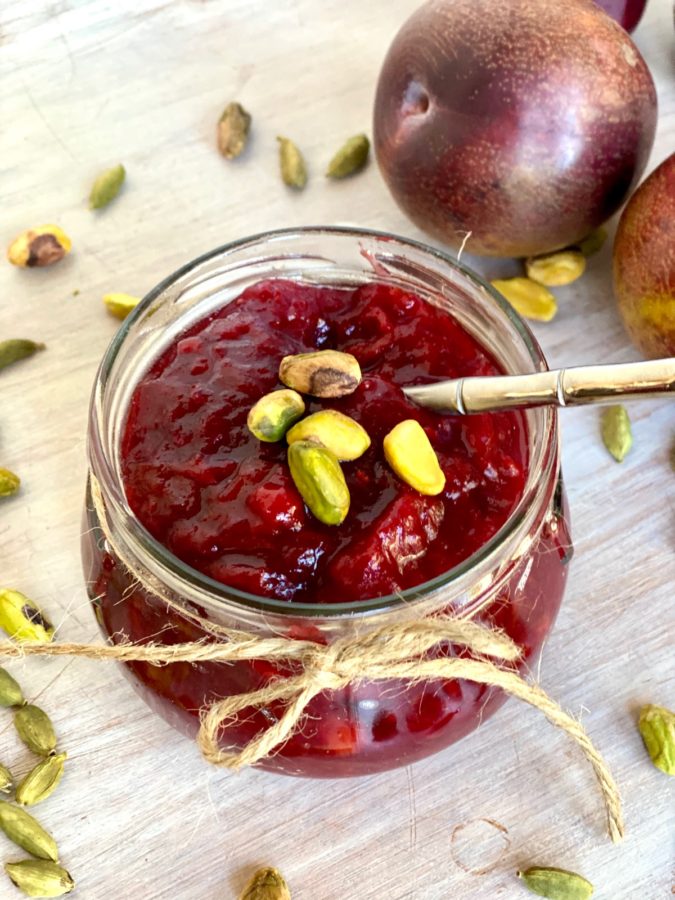 Fresh Red Plum Compote in jam jar with pistachio garnish.