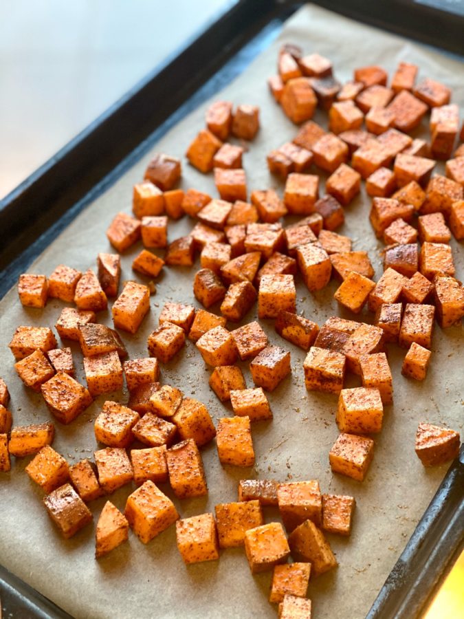 Chipotle spiced sweet potato chunks arranged on a parchment lined sheet pan