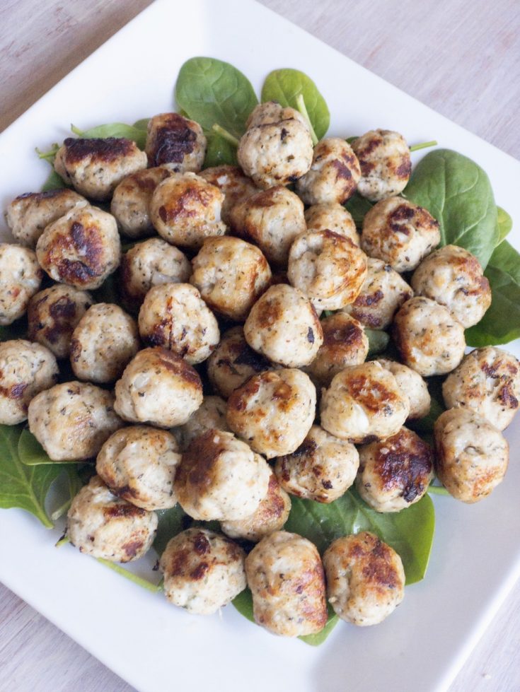 Lean ground turkey meatballs served on a platter of baby spinach leaves