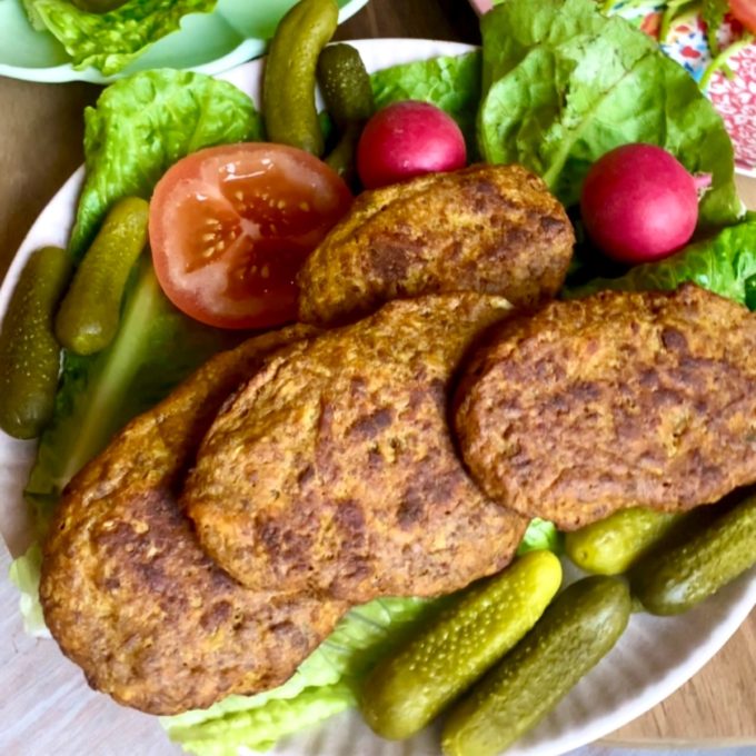 Baked kotlet served with pickles, radishes, tomato and lettuce